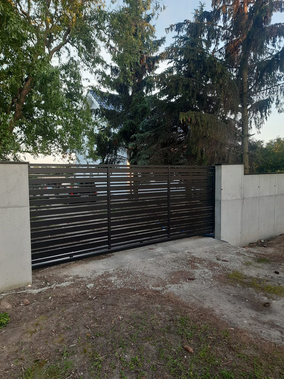 Brama z poziomymi lamelami między ścianami betonowymi